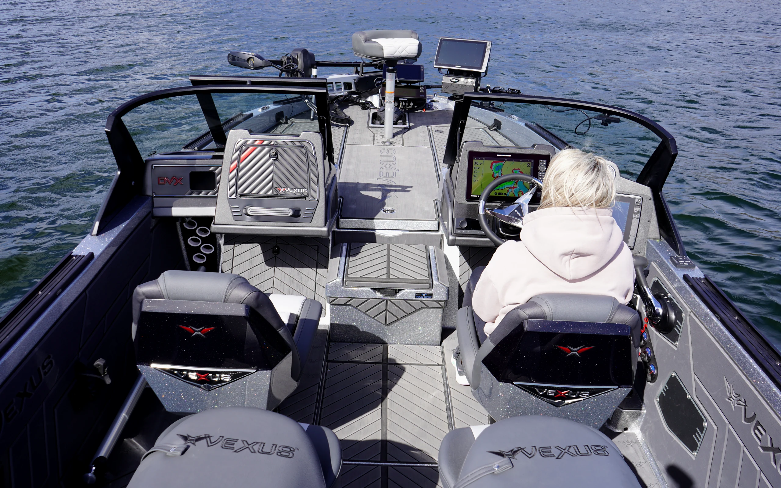 Inside the Vexus DVX 20S cockpit from the stern — four gray VEXUS seats, the walk-through windshield, and the helm station